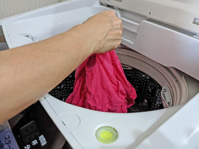 ピンクのTシャツを洗濯機から取り出す