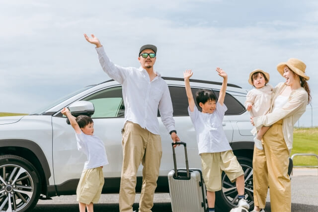 車の前で手を上げて楽しんでいる家族